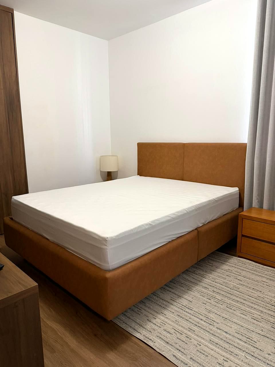 Cama estofada em courino caramelo com cabeceira sob medida, instalada no quarto de uma cliente